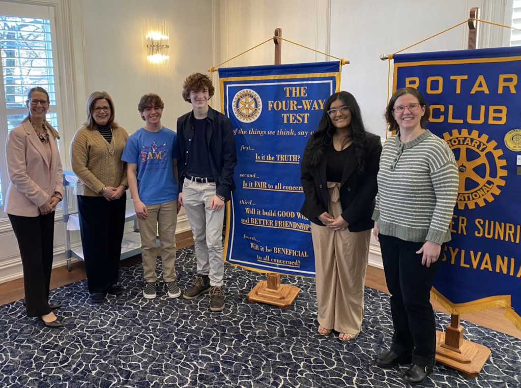 Students and staff posing in front of a sign for the Four-Way Test speeches 